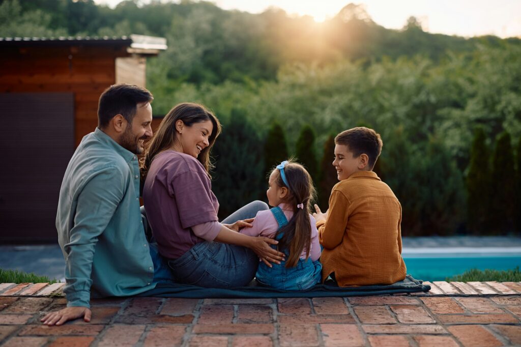 Happy family relaxing by the pool in their backyard.